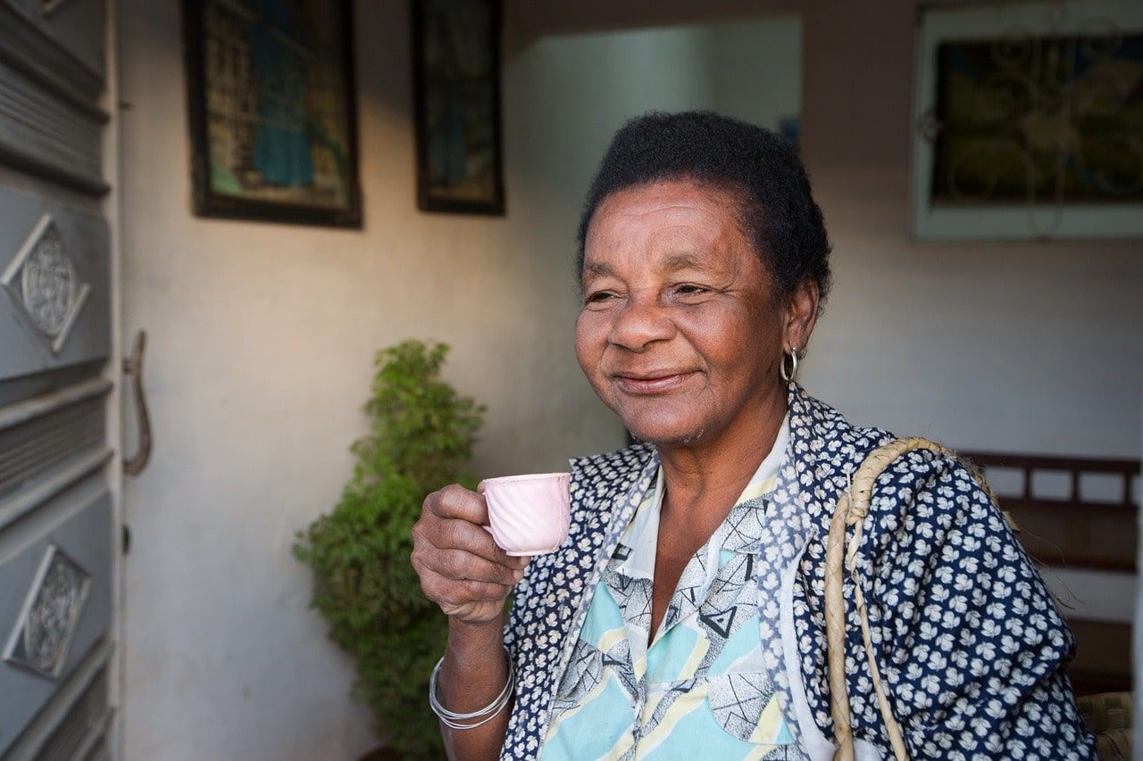 Grandmother holding a teacup, lost in deep thought.