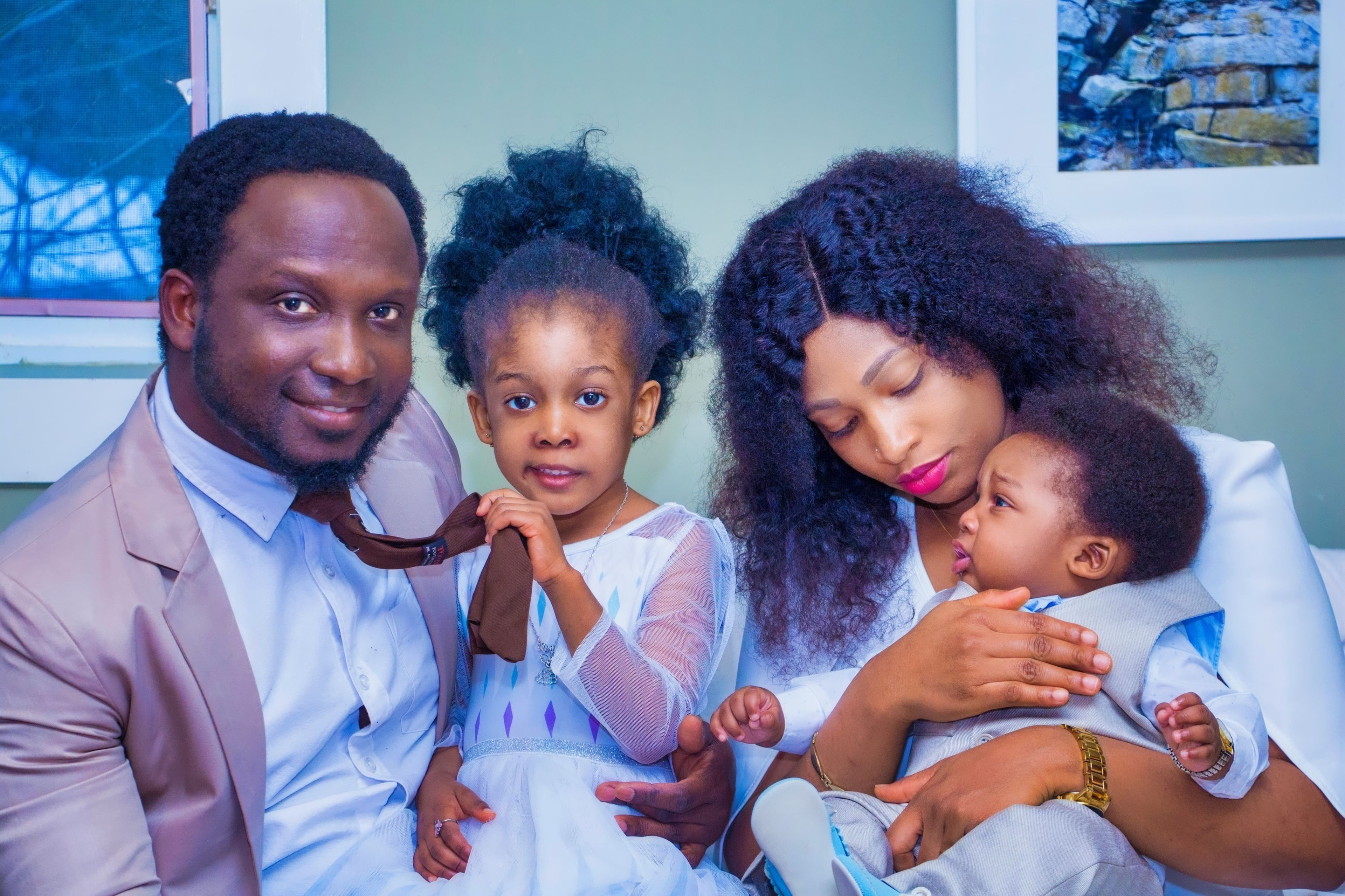 Family portrait of a mother, father, daughter, and toddler posing happily together.